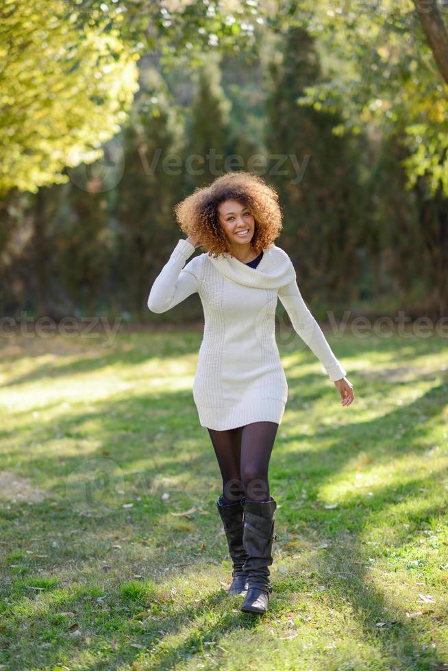 ung flicka med afro frisyr promenader i en stadspark foto