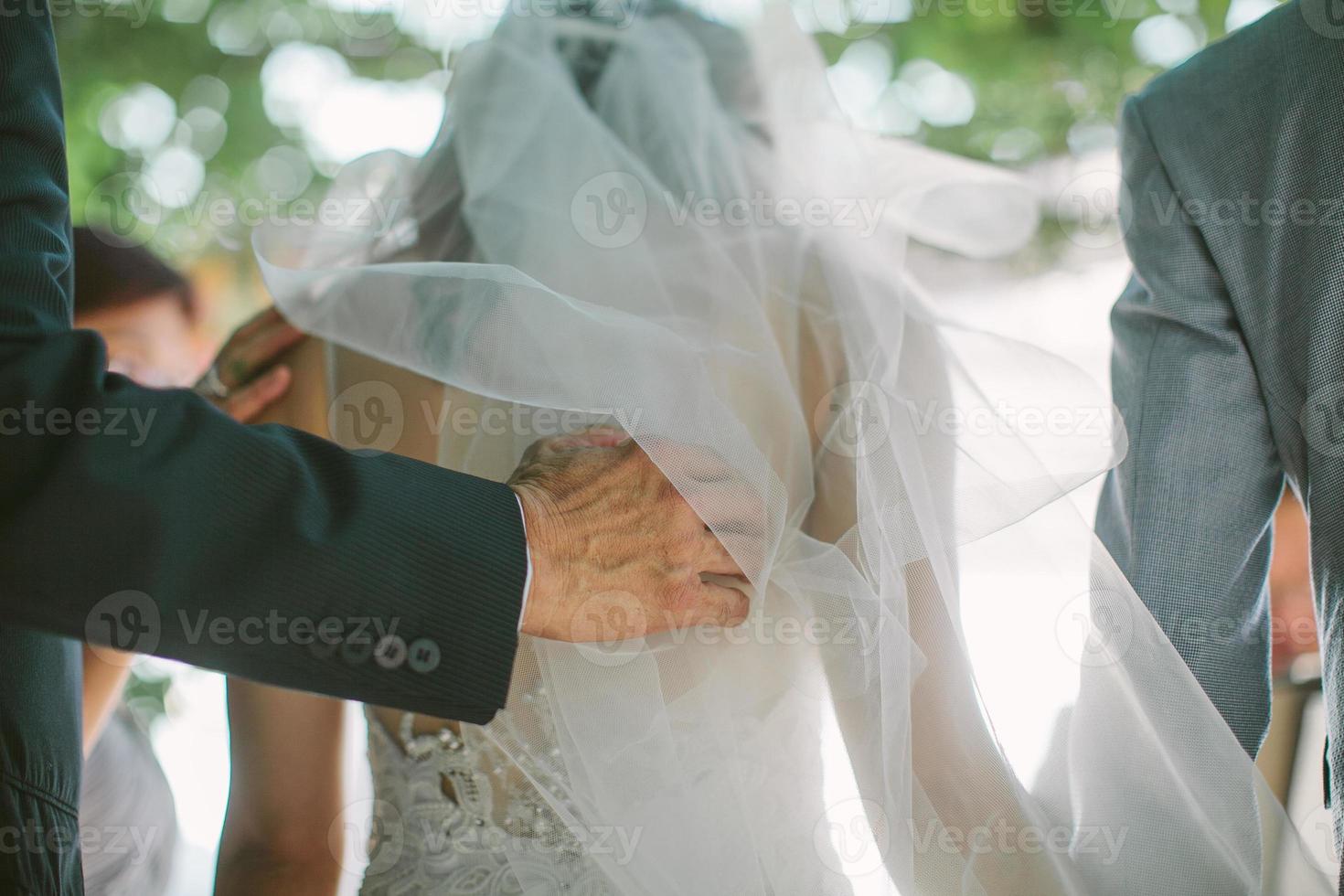 en far rörde mjukt ryggen på sin dotter, som är bruden, under en bröllopsceremoni foto
