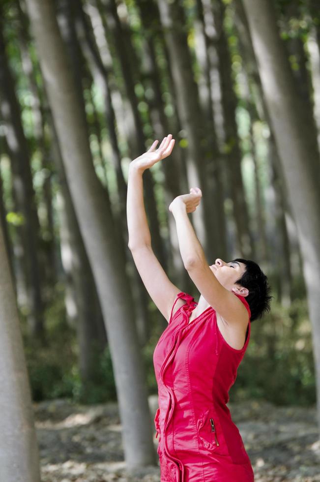 kvinna klädd i rött, mediterar i skogen foto