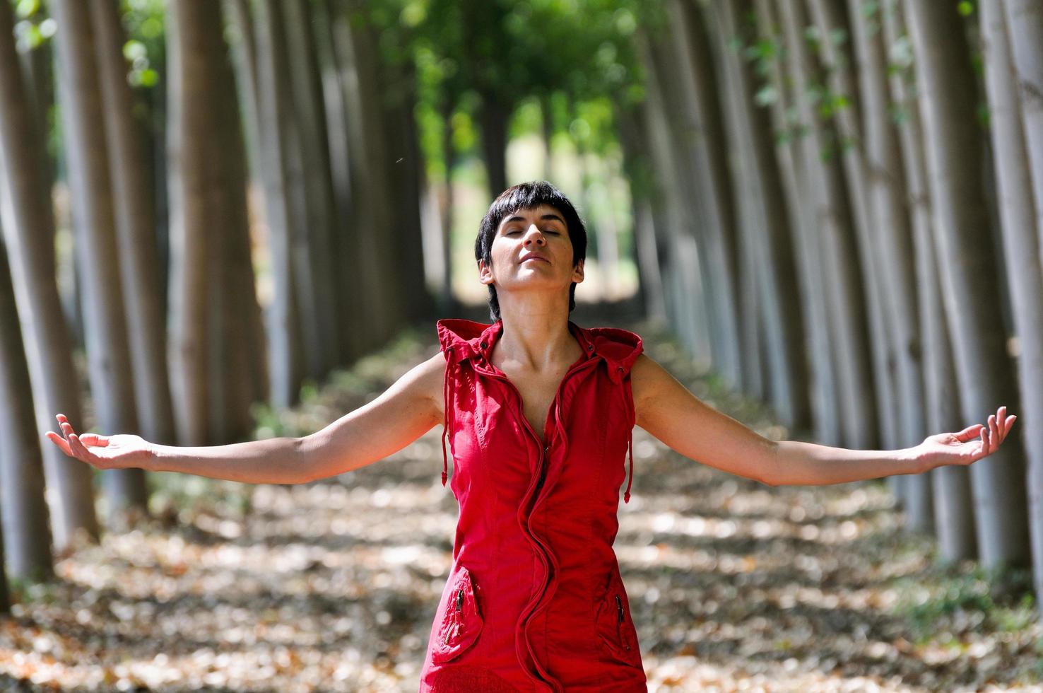 kvinna klädd i rött, mediterar i skogen foto