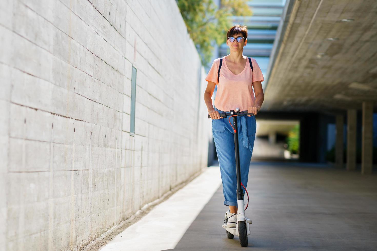 kvinna åker runt i stan på en elektrisk skoter foto