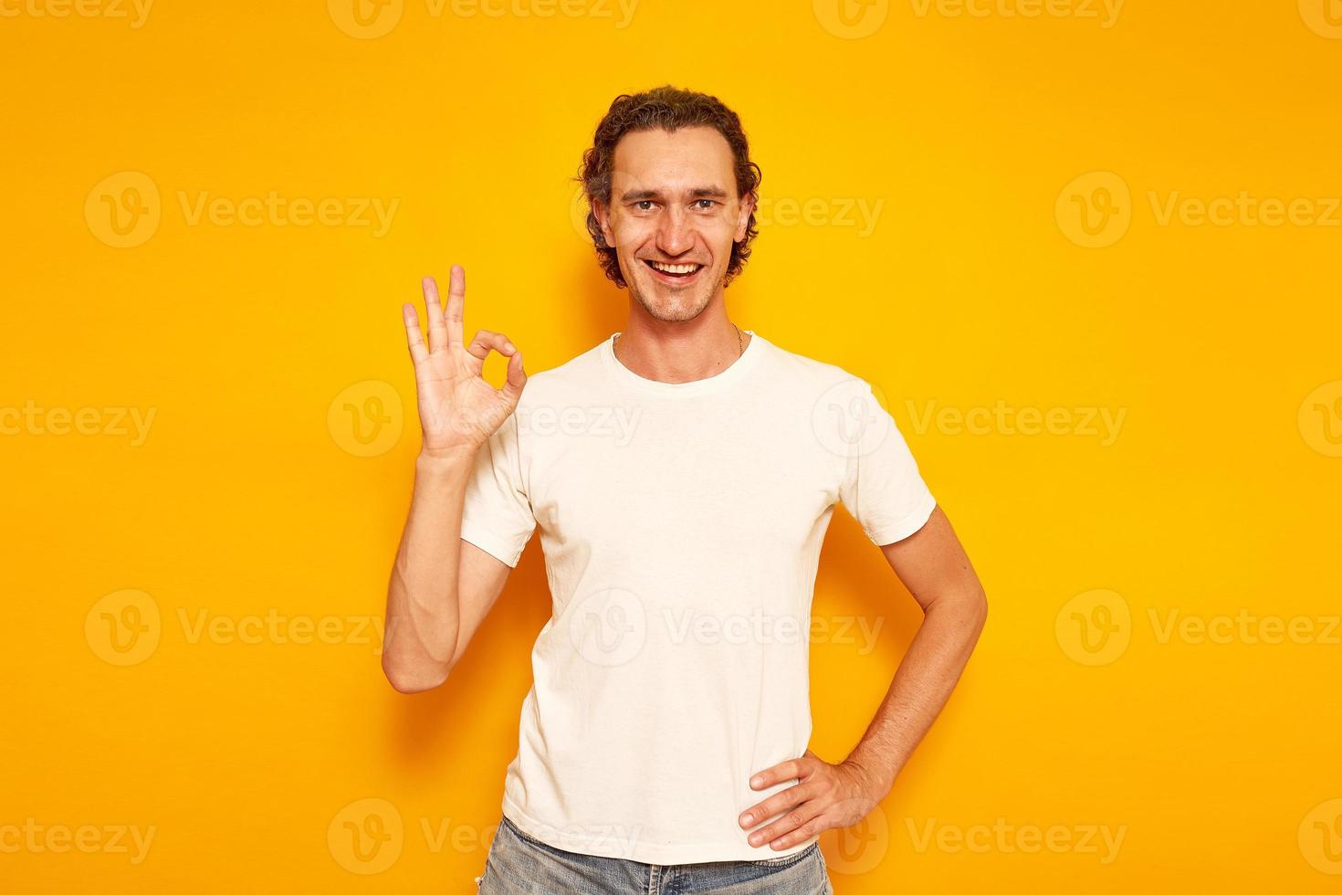 en glad, glad man i lediga kläder visar en skylt med handen ok, allt är bra. isolerad på en gul bakgrund med ett utrymme för text. begreppet människor, fyndköp, semester foto