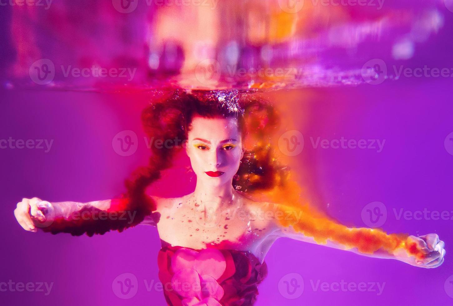 surrealistiskt porträtt av ung attraktiv kvinna med luftbubblor under vattnet i färgglatt vatten med bläck i poolen foto