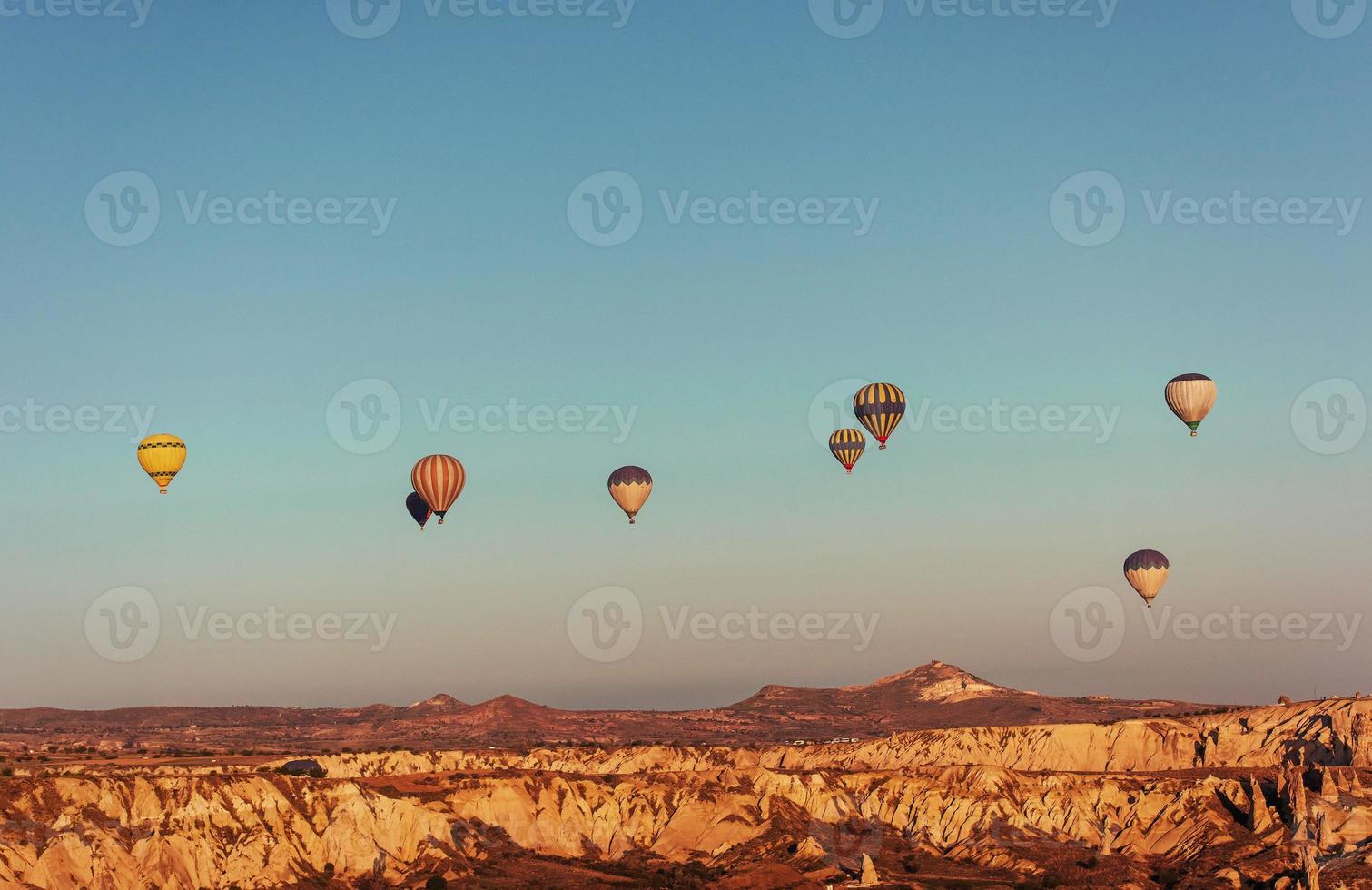 varmluftsballong som flyger över klipplandskap på cappadocia Turkiet. foto