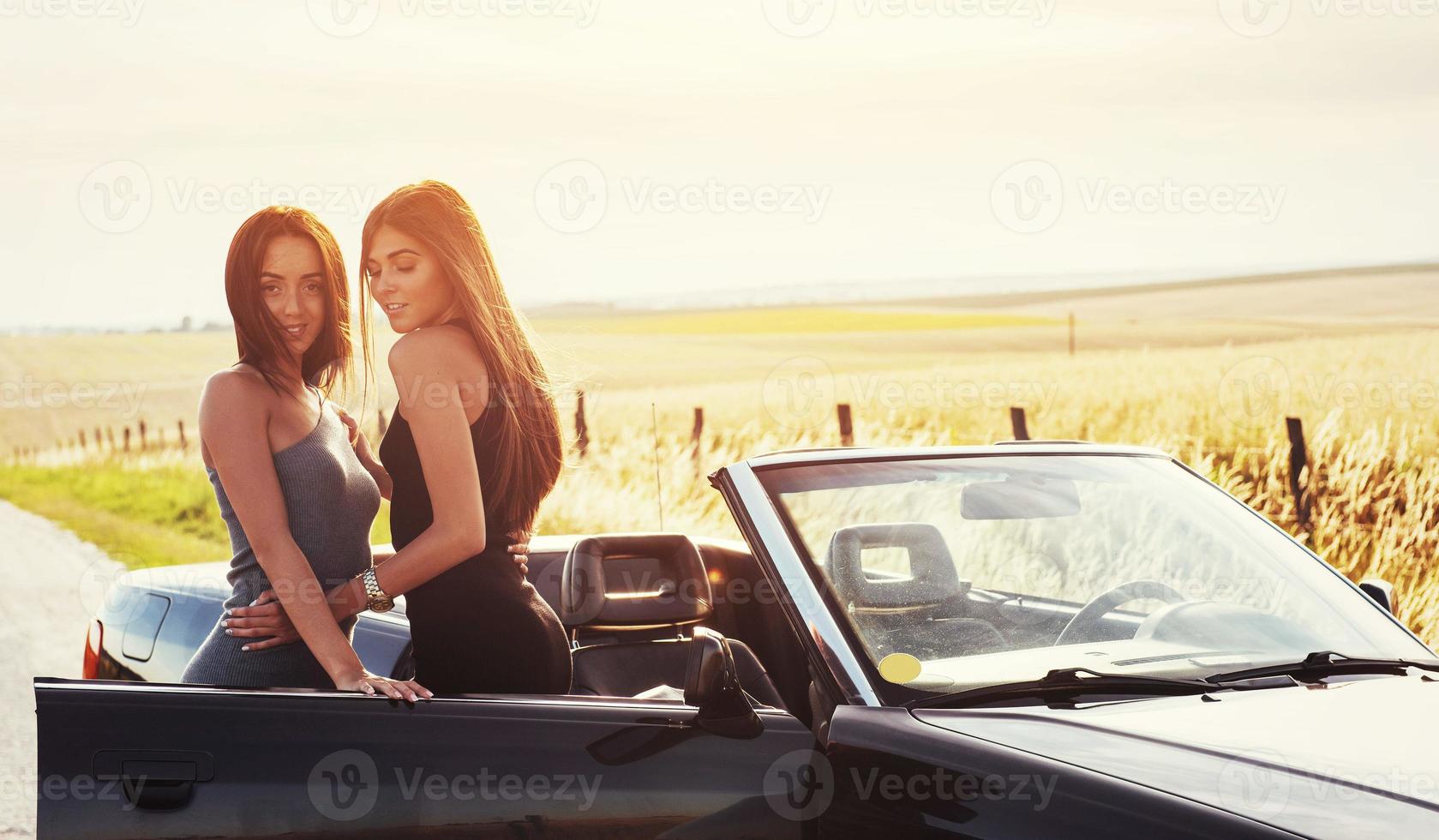 två sexig brunett kvinna som står nära hennes bil foto
