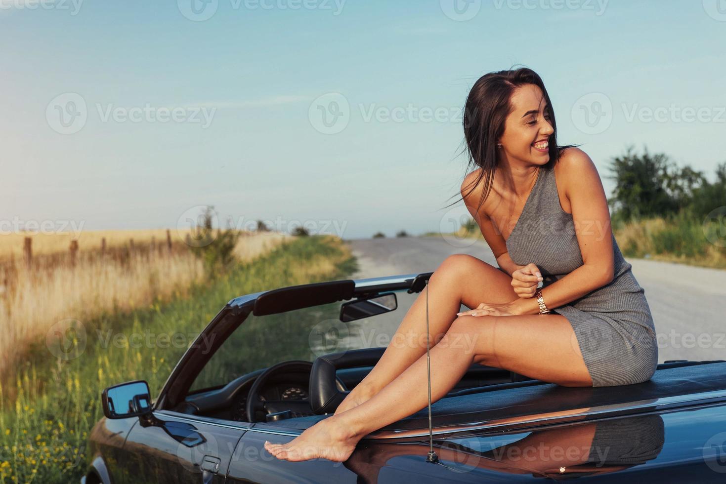 vacker ung kvinna poserar nära en bil på vägen foto