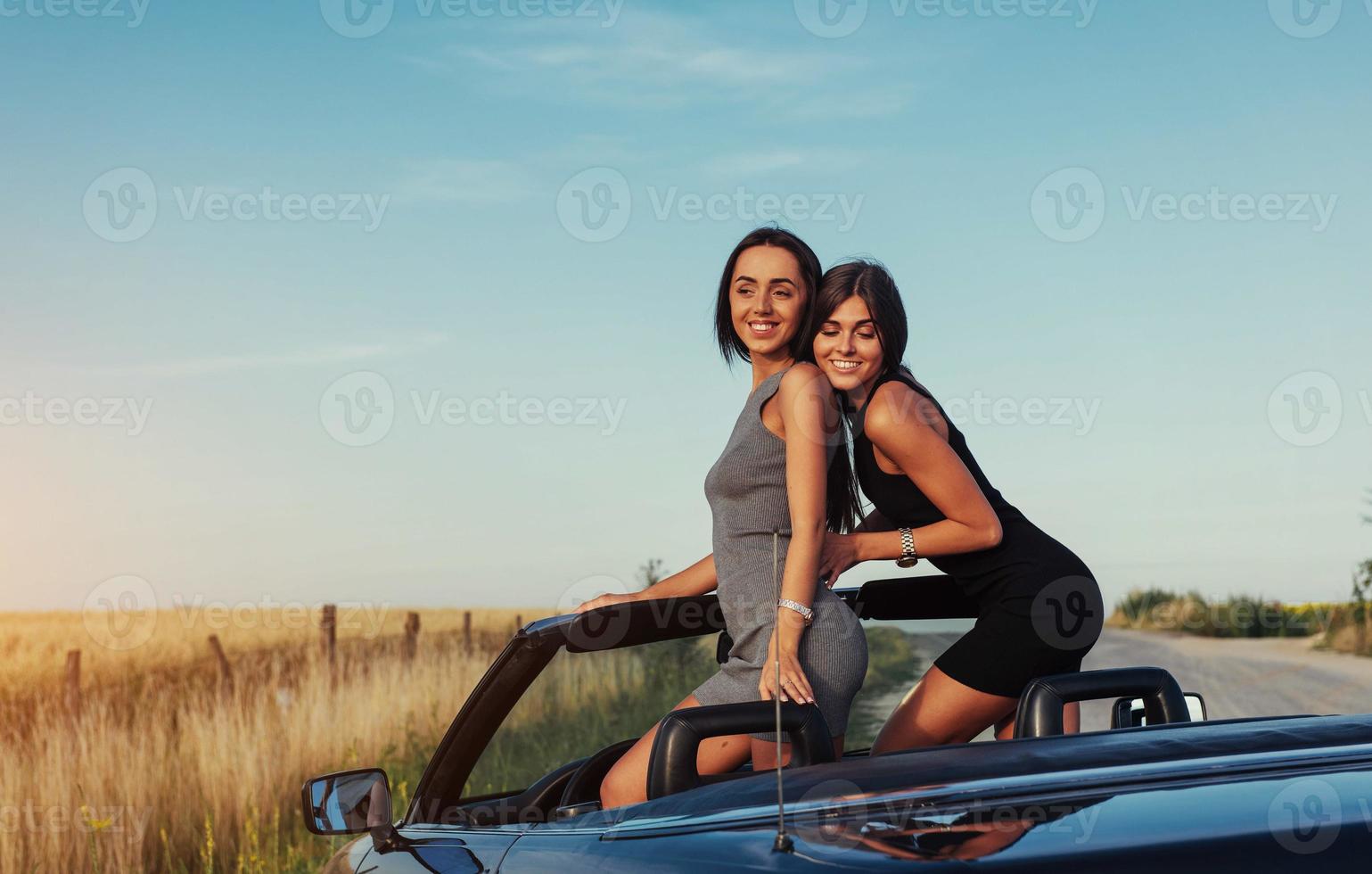 vackra två kvinnor som sitter i en cabriolet foto
