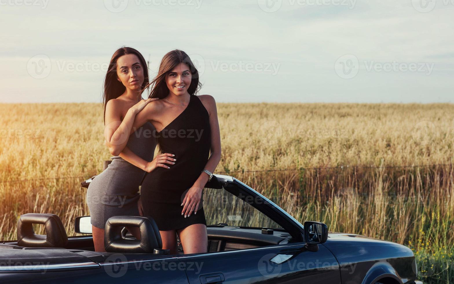 flickor poserar för kameran i en svart cabriolet foto