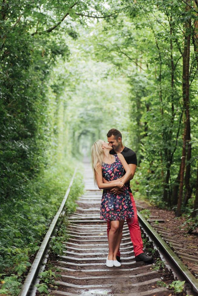 älskande par i en tunnel av gröna träd på järnvägen foto