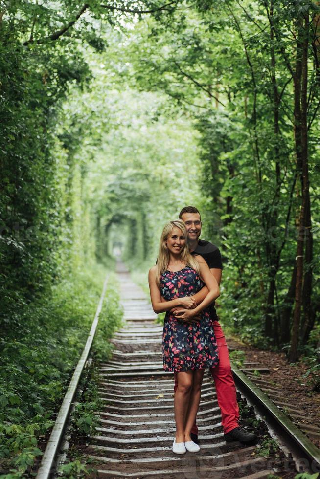 älskande par i en tunnel av gröna träd på järnvägen foto