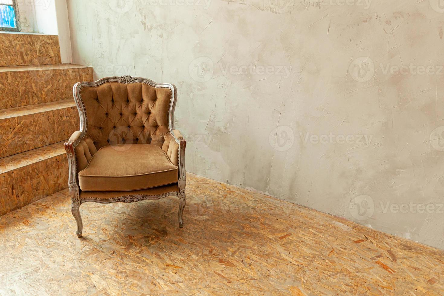 vackert lyxigt klassiskt biege rent inre rum i grungestil med brun barockfåtölj. vintage antik brun-grå stol som står bredvid väggen. minimalistisk hemdesign. foto
