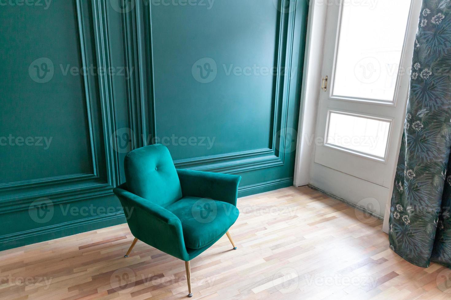 vackert lyxigt klassiskt blågrönt rent inre rum i klassisk stil med grön mjuk fåtölj. vintage antik blågrön stol som står bredvid smaragdväggen. minimalistisk hemdesign. foto