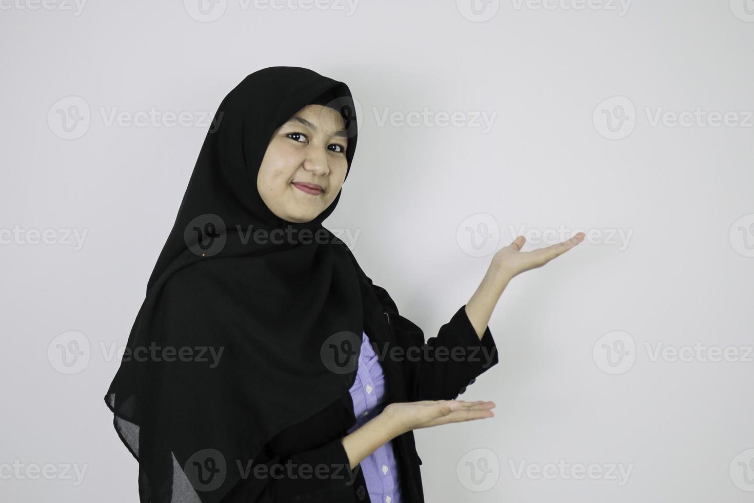 glad ung asiatisk islam kvinna som bär huvudduk är leende och pekar bredvid. foto
