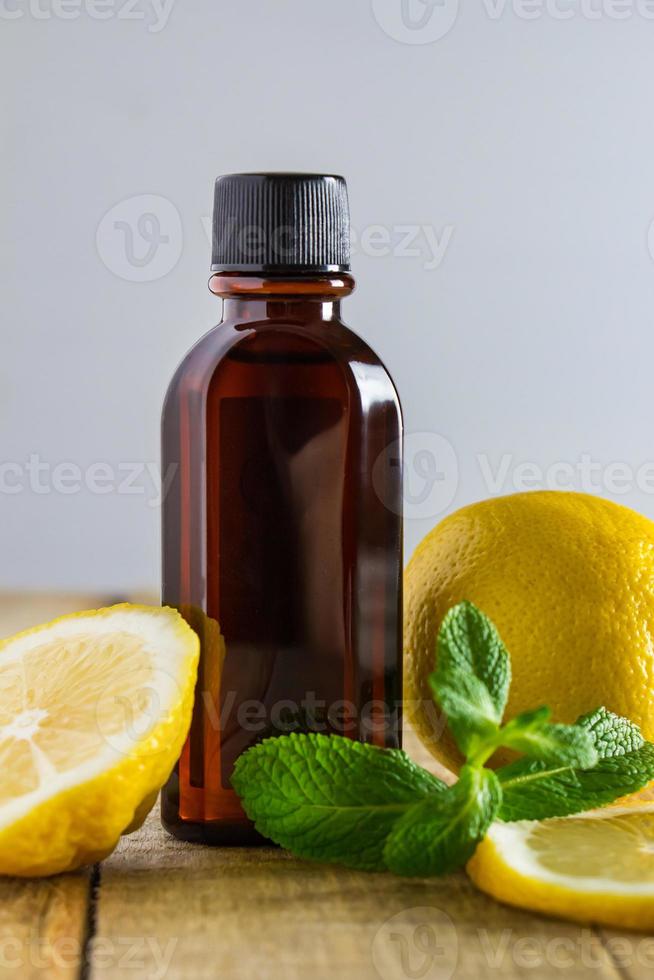 aromatisk olja med citron och mynta på trä bakgrund. foto