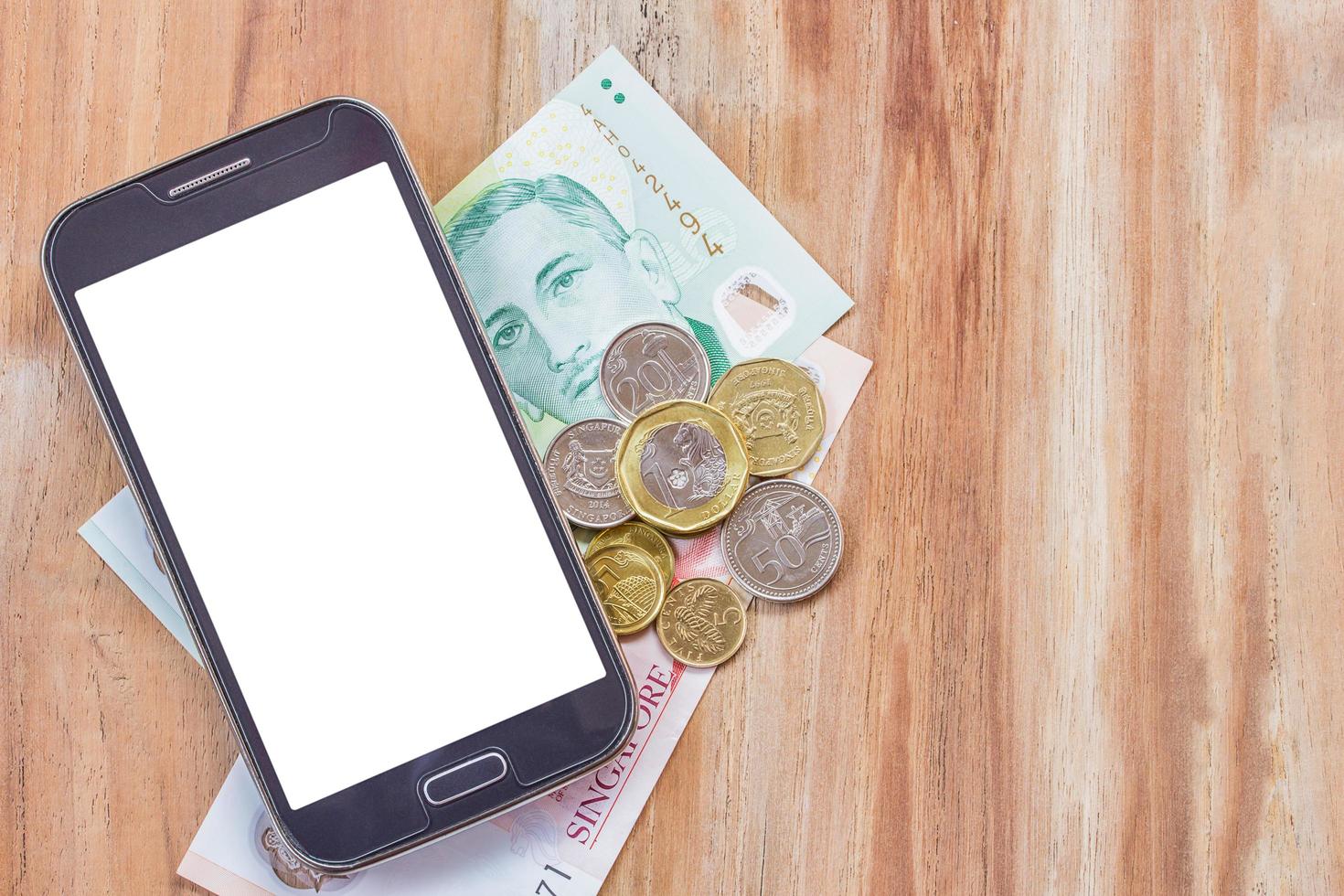 smart telefon och singapore dollar på träbord foto