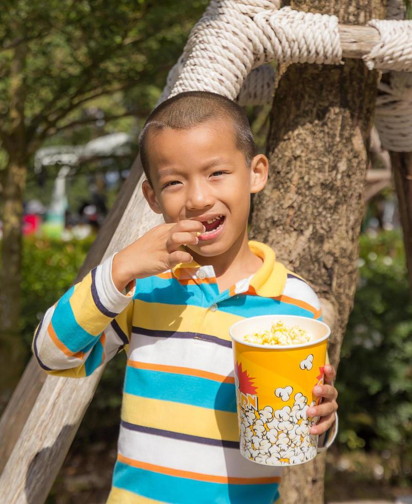 asiatisk pojke äter äta popcorn foto
