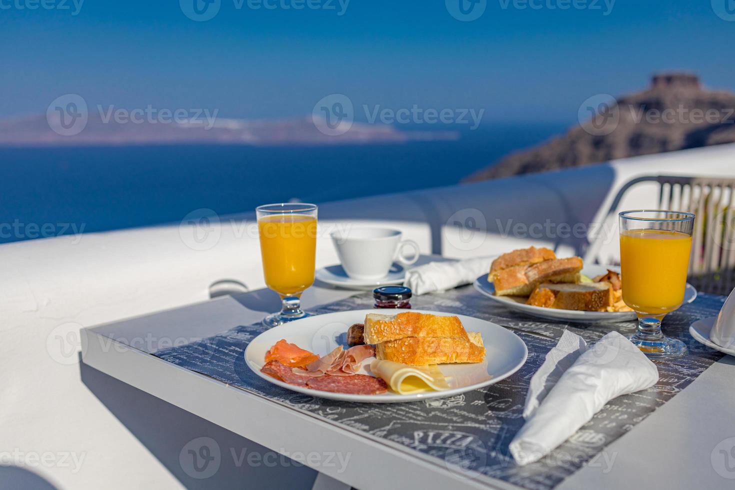 frukosttid i santorini på hotellet. lyxig stämning med färsk omelett och frukt med juice över havsutsikt. lyxig sommar reser semester bakgrund. glada slappna av vibbar, par morgon närbild bord foto