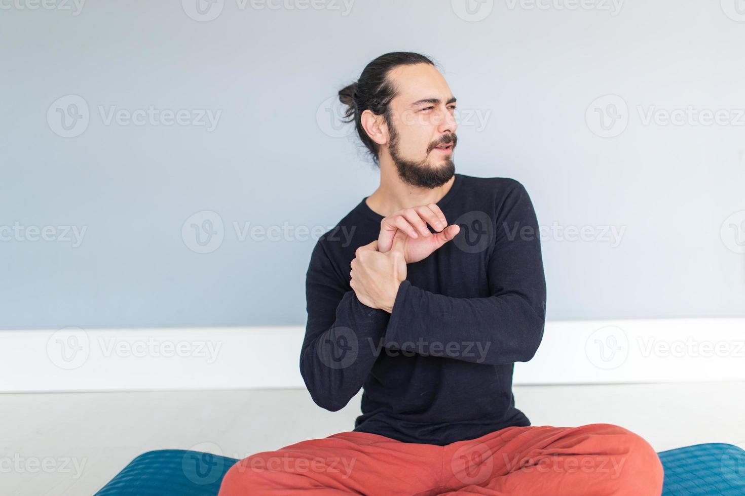 ung atletisk man lider av smärta från sin handled under träning eller yoga foto