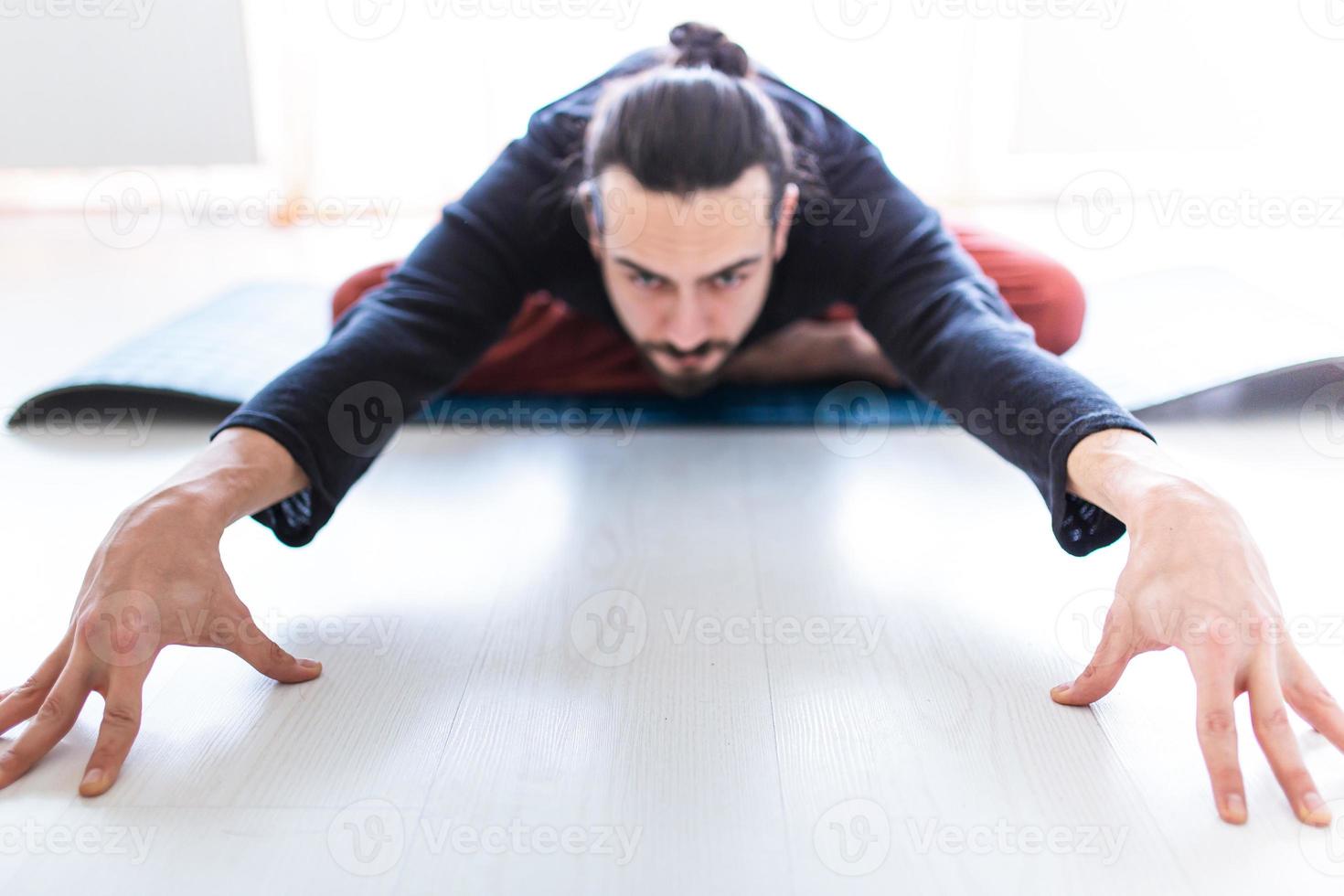 ung kaukasisk långhårig vit man utför yoga i en studio eller ett hus. foto