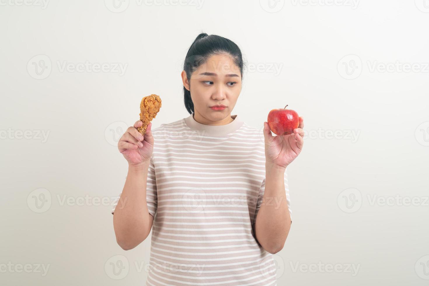 asiatisk kvinna med stekt kyckling och äpple till hands foto