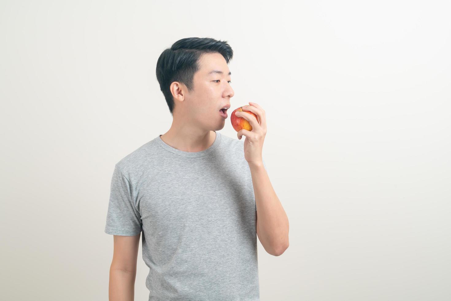 ung asiatisk man med ett glas vatten och äpple till hands foto