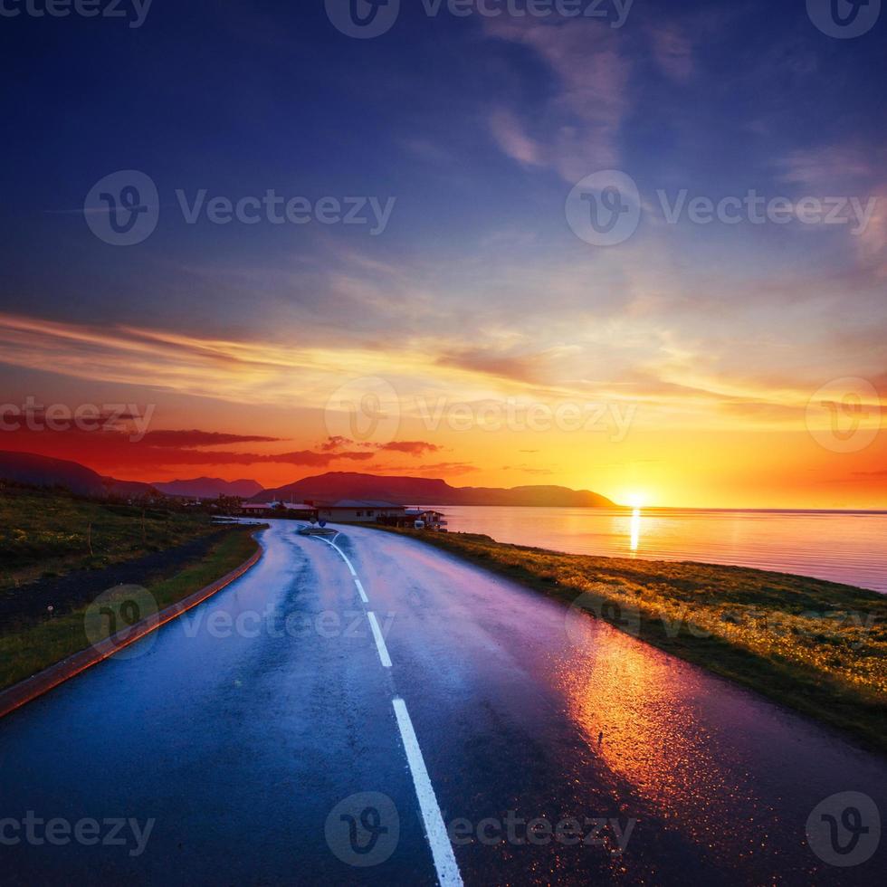 asfaltväg längs havet vid solnedgången Island foto