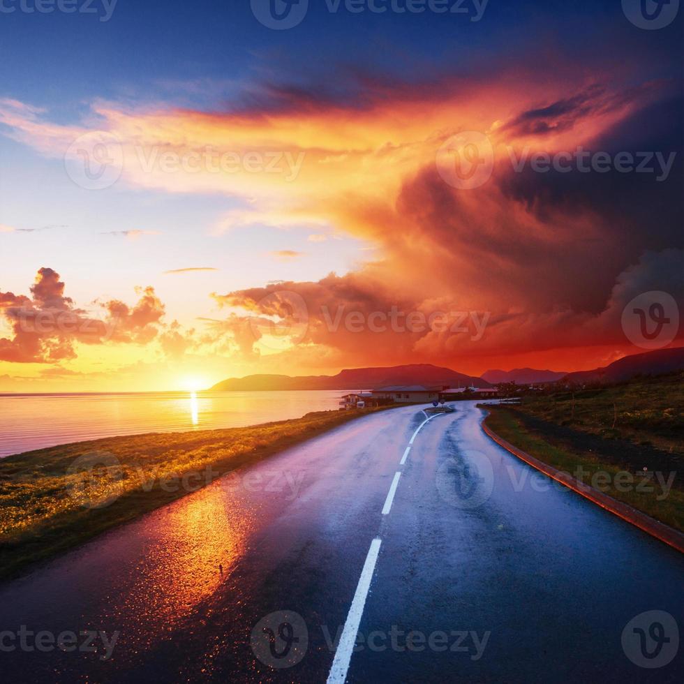 asfaltväg längs havet vid solnedgången Island foto