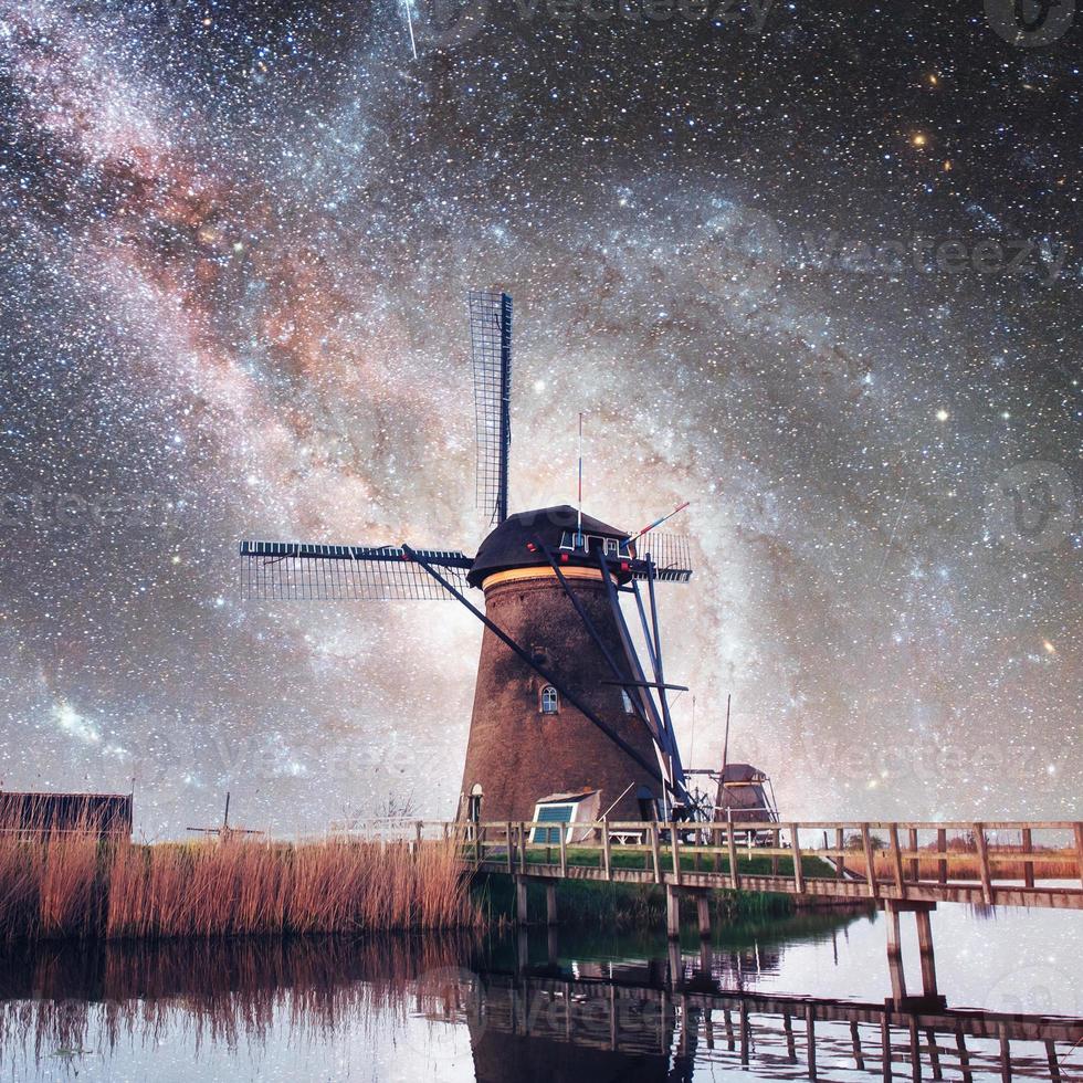 holländska kvarnen på natten. stjärnbeströdd himmel. med tillstånd av nasa. holland foto