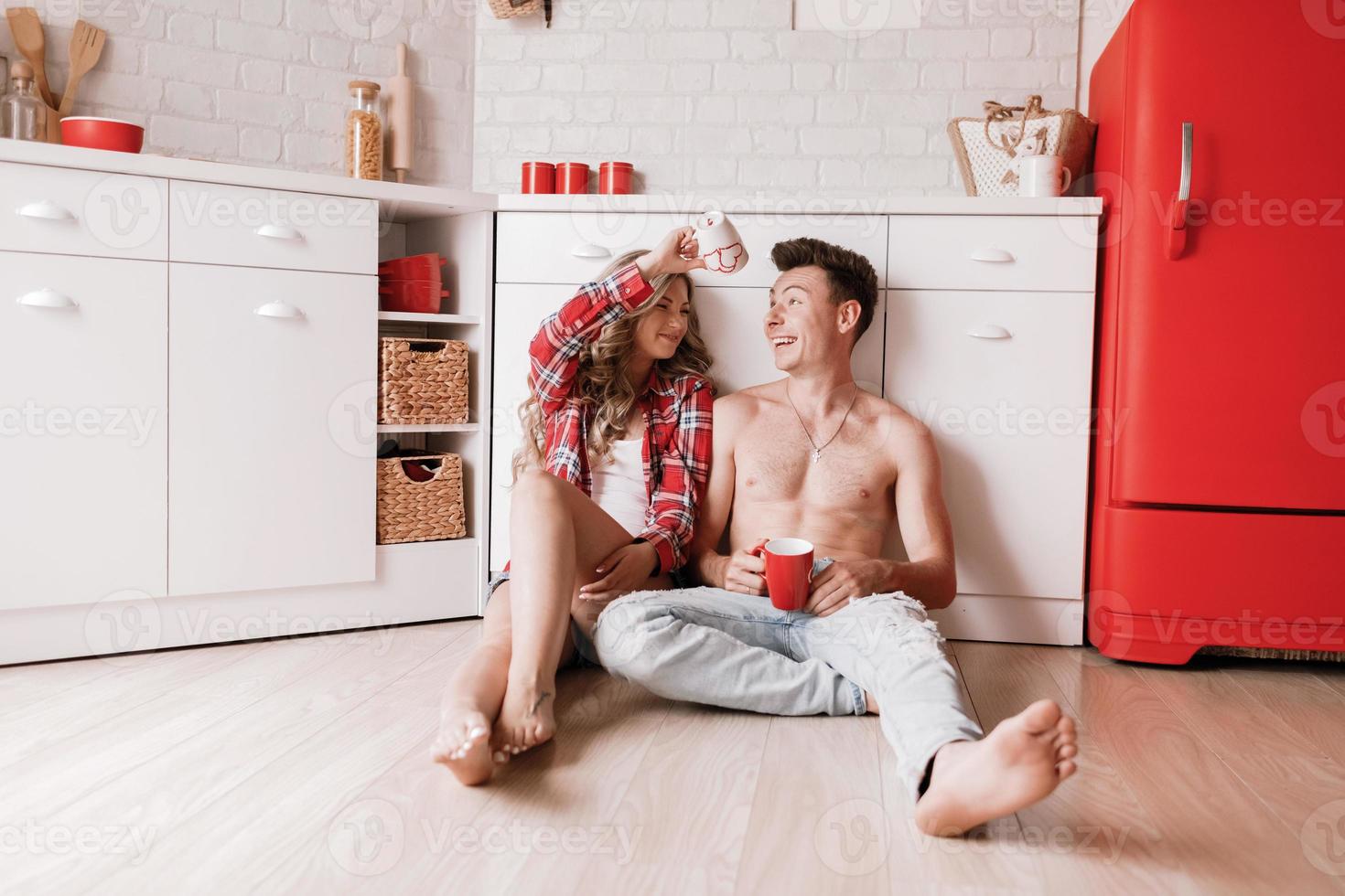 ungt par fikar tillsammans hemma i köket. njuter av en trevlig morgon tillsammans. vackert ungt par ler medan du sitter i köket tillsammans och äter frukost. foto
