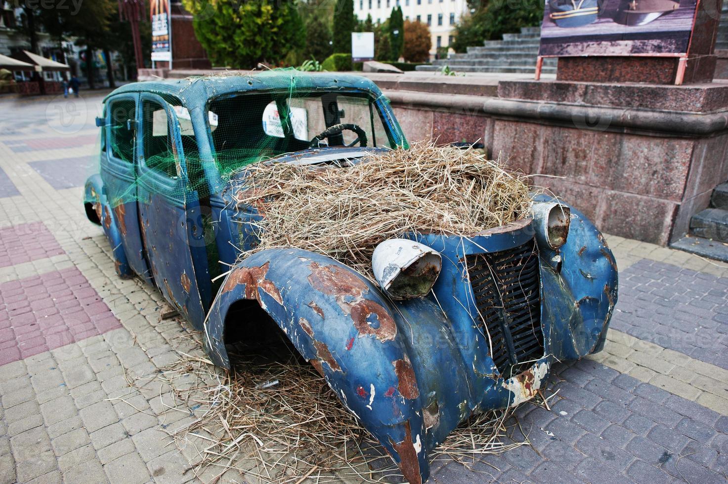 gammal övergiven bil med hö på motorn foto