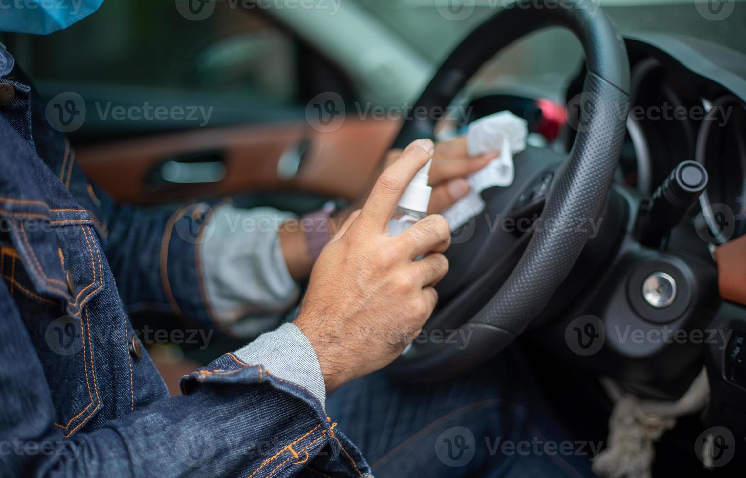 asiatisk man använder sprayalkohol för att rengöra bilen för skydd mot coronavirus foto