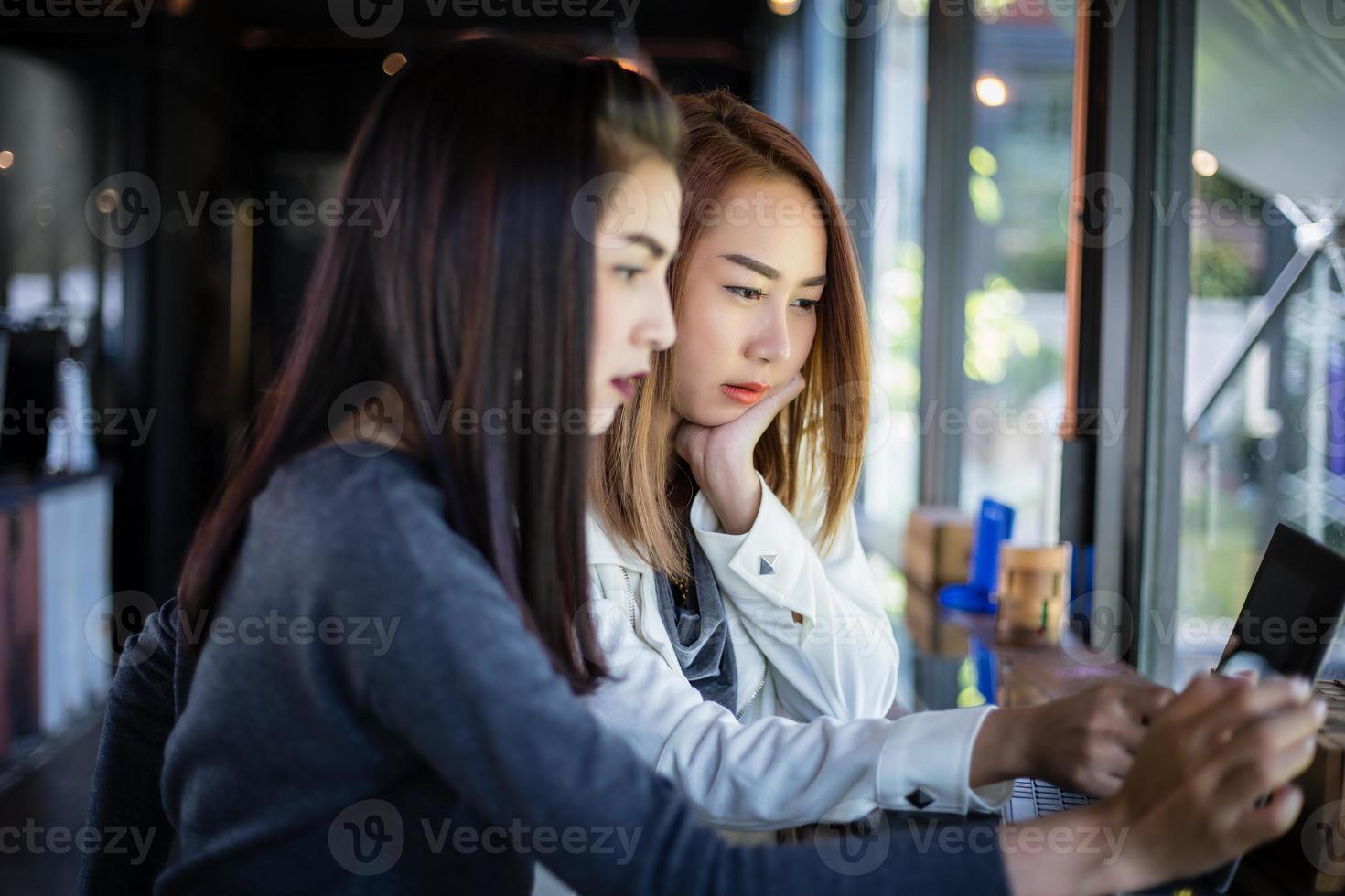 två asiatiska affärskvinnor som använder anteckningsbok och diskussion om det viktiga kontraktet på kaféet foto