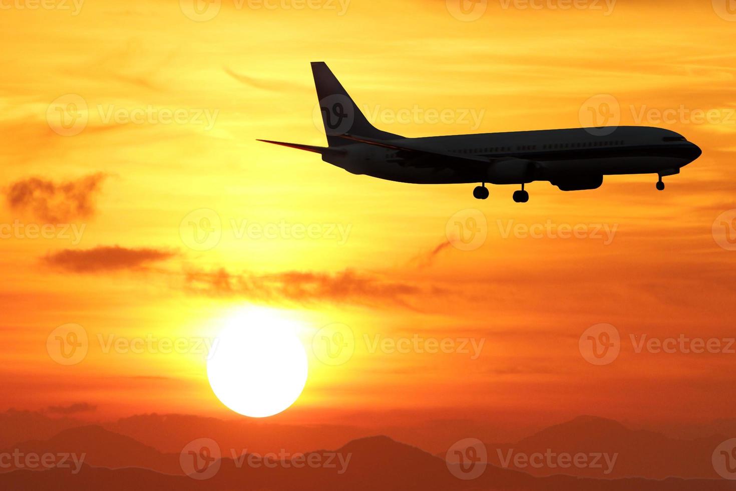 siluett av flygplan i luften med solnedgång över bergen med en vacker gyllene himmel. foto