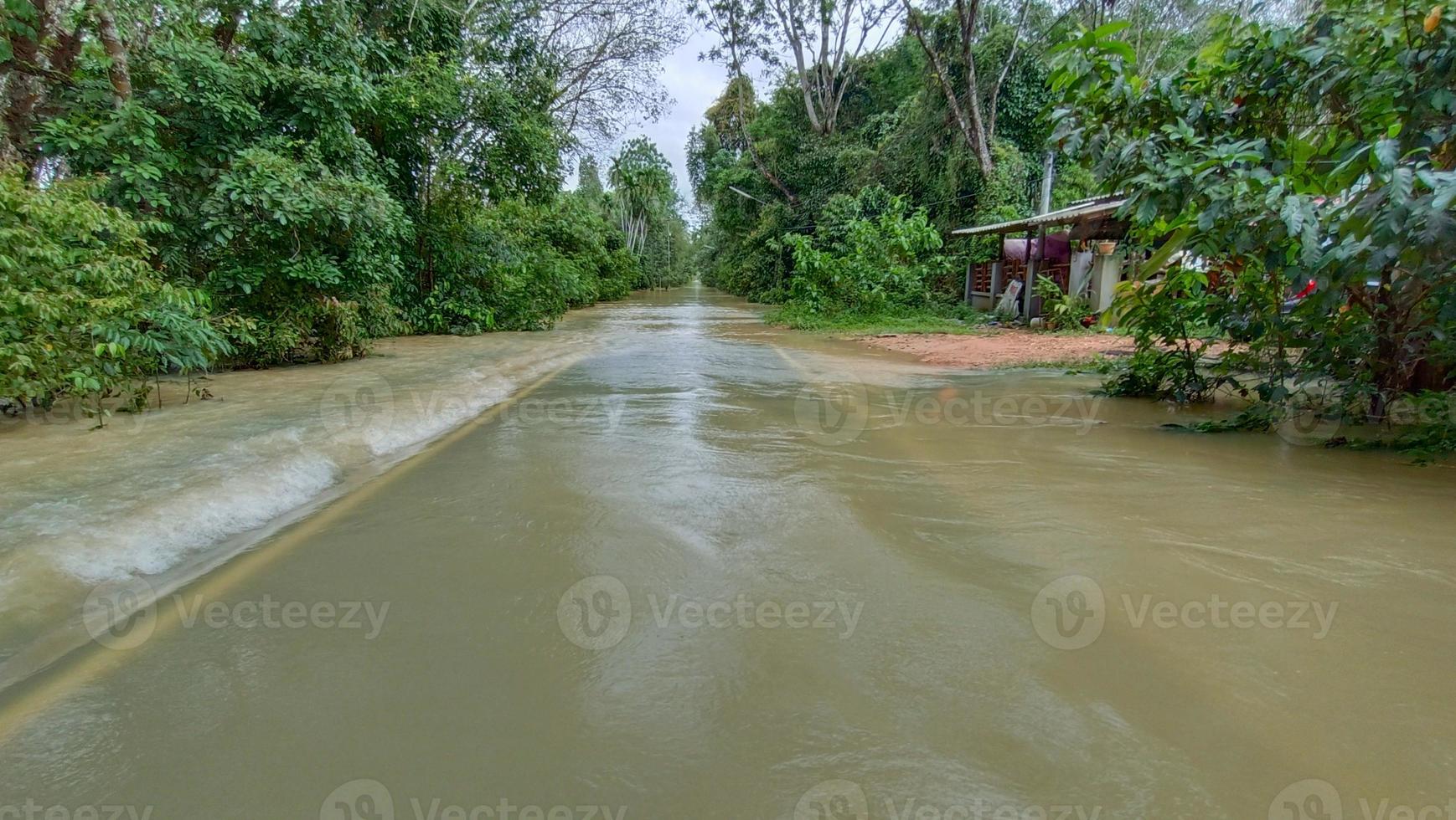 översvämningsvattnet rinner tvärs över gatan foto