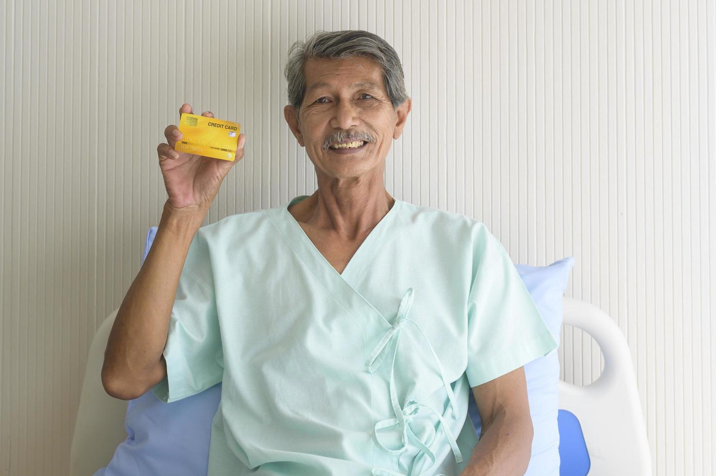 en asiatisk senior patient man visar kreditkort på sjukhus foto