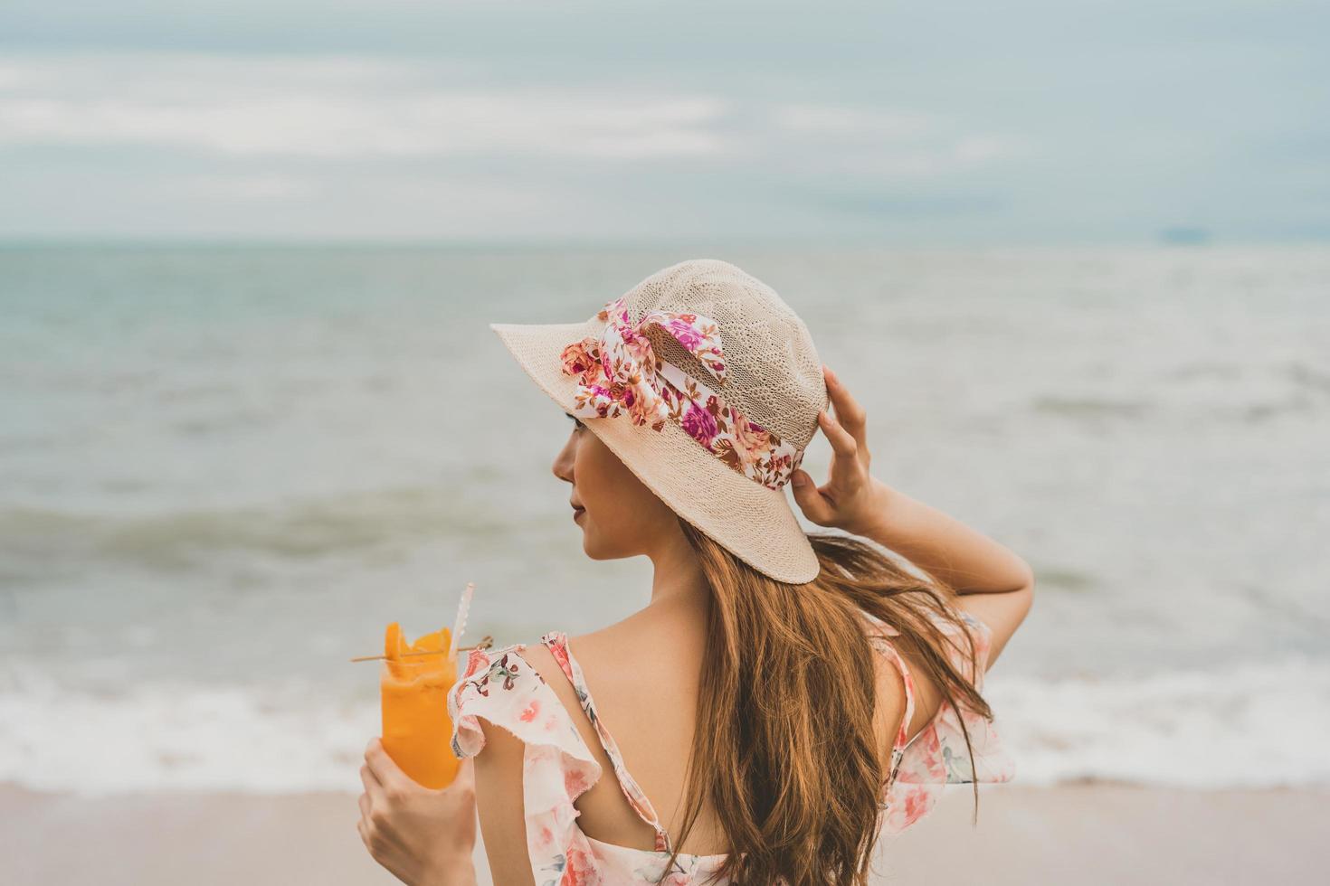 slappna av kvinna dricker uppdatera orange cocktail på stranden foto