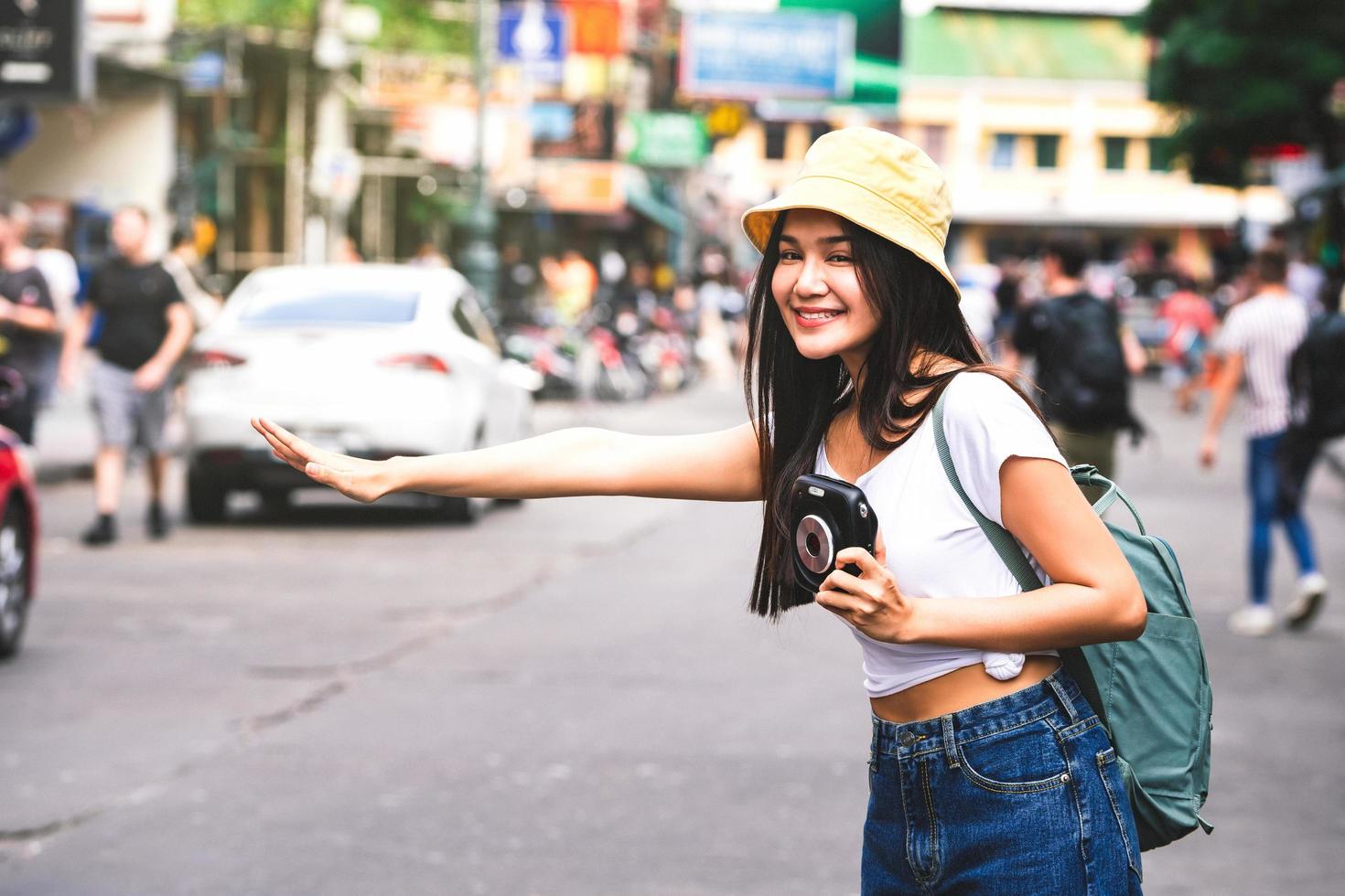 ung asiatisk kvinna flagga ner en taxi på khaosan foto