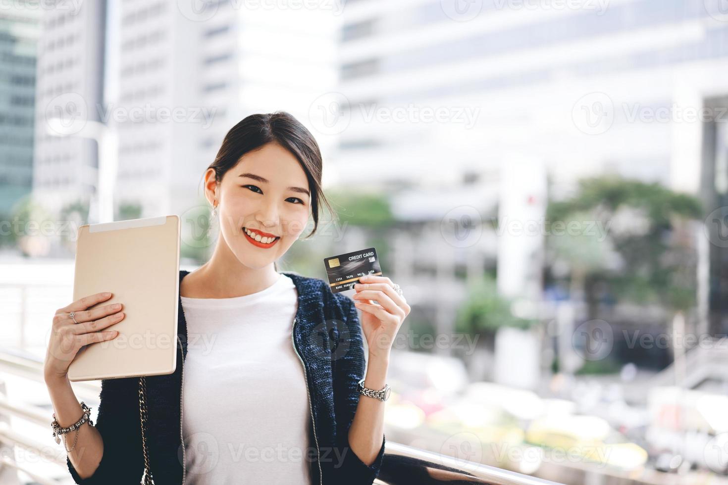 glad ung vuxen asiatisk kvinna konsument använder kreditkort och digital surfplatta för shopping. foto