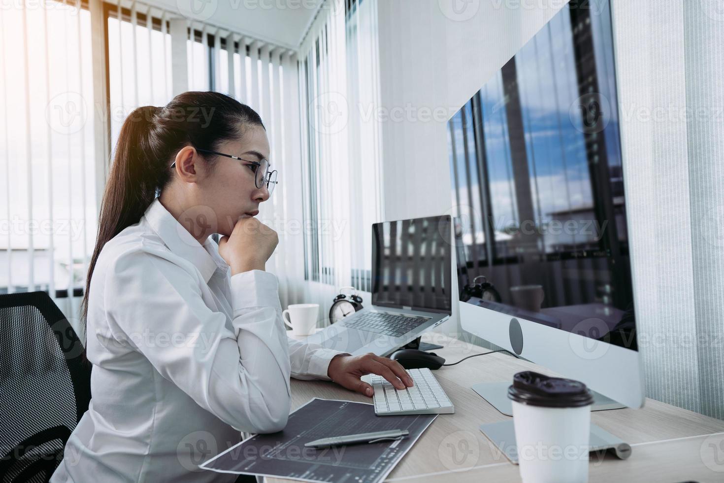 asiatisk kvinnlig mjukvaruutvecklare är orolig för att analysera kodbaserade system på sitt kontor. foto