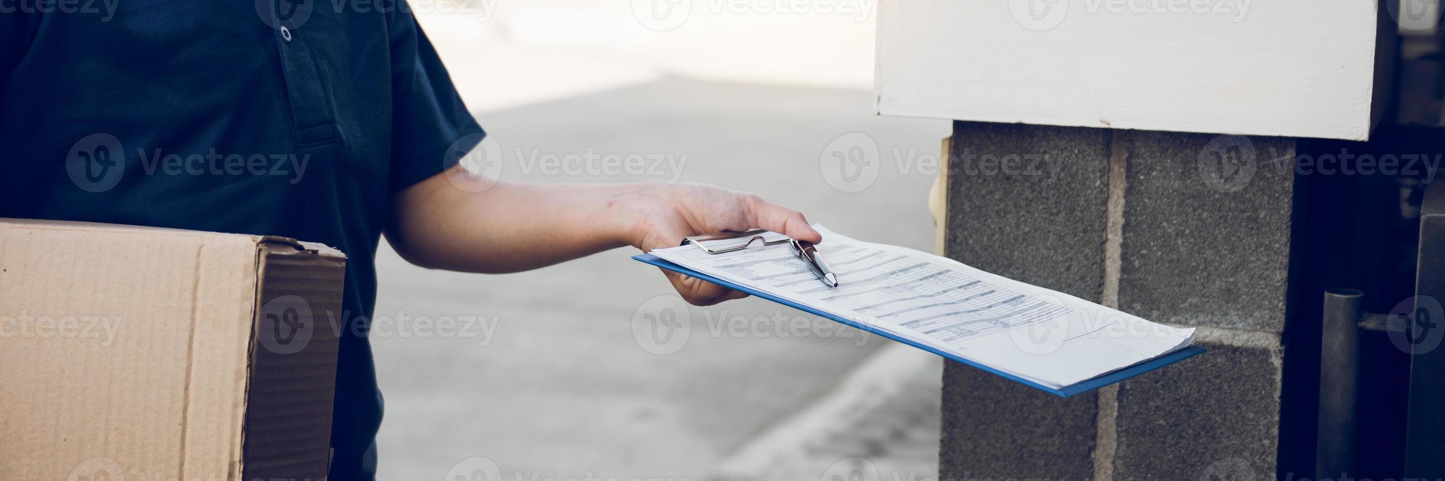 ung asiatisk man ler medan han levererar en kartong till kvinnan som håller dokumentet för att underteckna signatur. foto