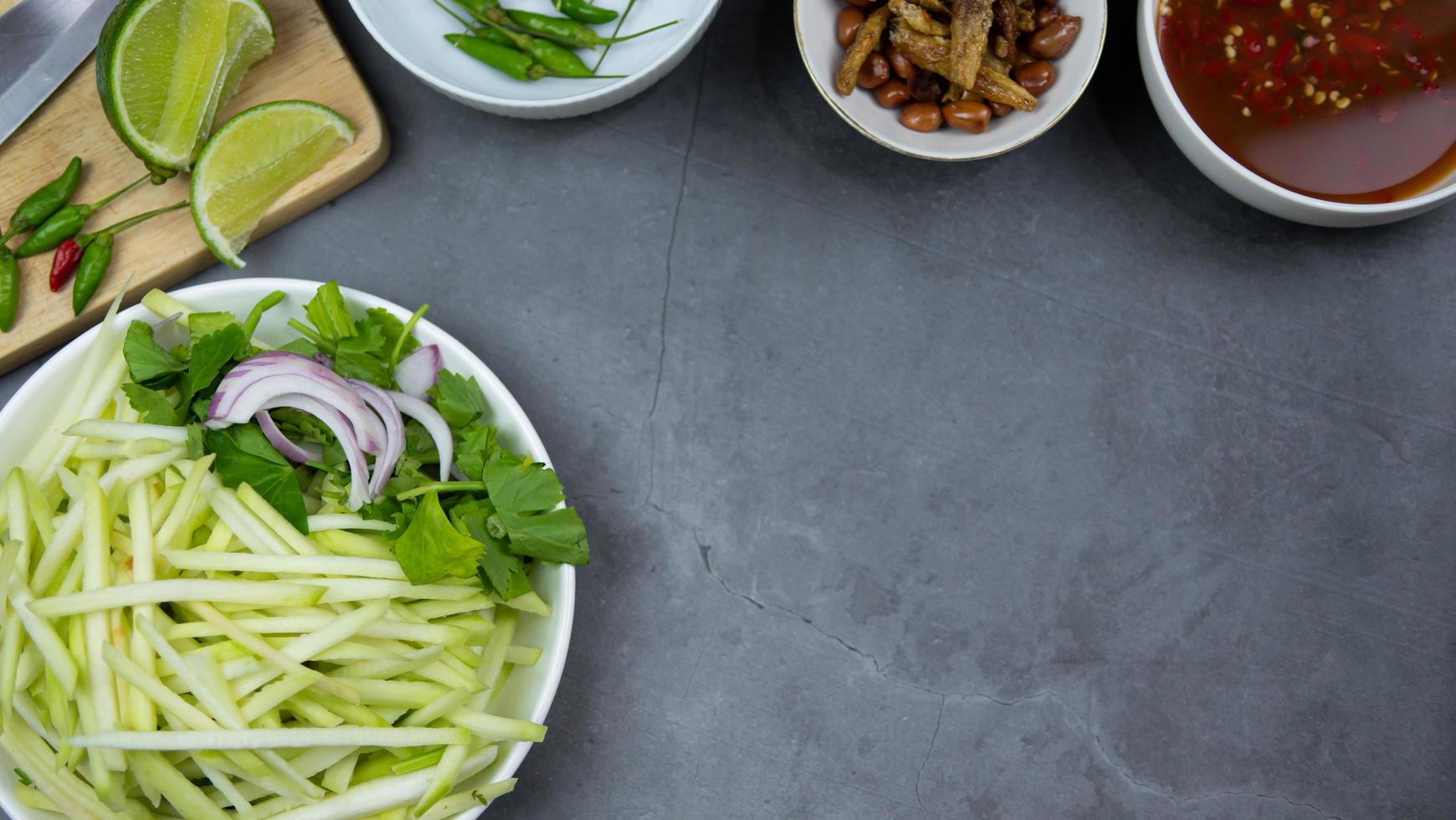 mums, mangofoto toppvyer matarrangemang. kryddig salladsmat, toppad med stekta nötter och krispig fisk. huvudingredienserna är rå mango, limejuice, färsk chilipulver, fisksås, socker att blanda. foto