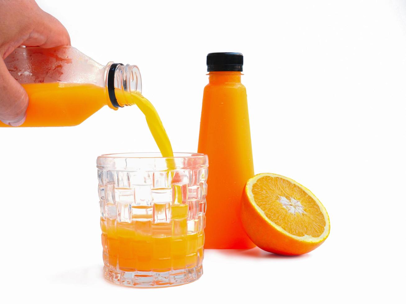 häll apelsinjuicen i en glasburk på vit bakgrund och ha apelsinjuiceflaskan redo. apelsin halverad som bakgrund foto