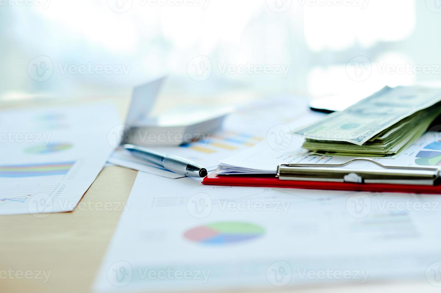 affärsdokument, ekonomiska grafer och grafer på skrivbordet. blockerad med flera dollarinsättningar. är affärsmannens mål. foto