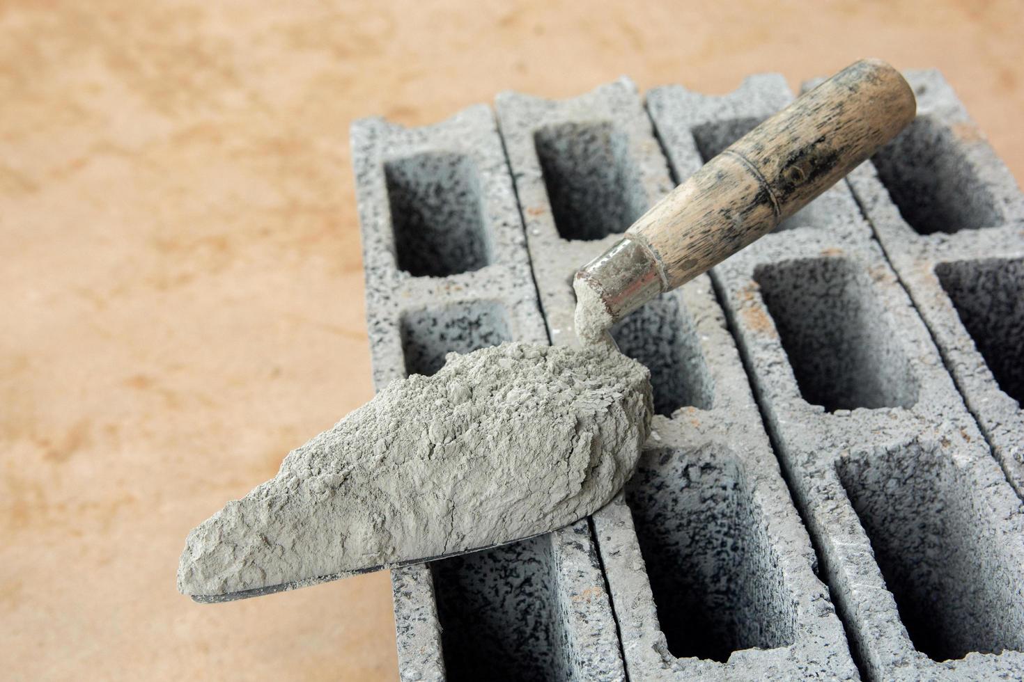 cementpulver eller murbruk med murslev läggs på betongstenen för byggnadsarbete. foto