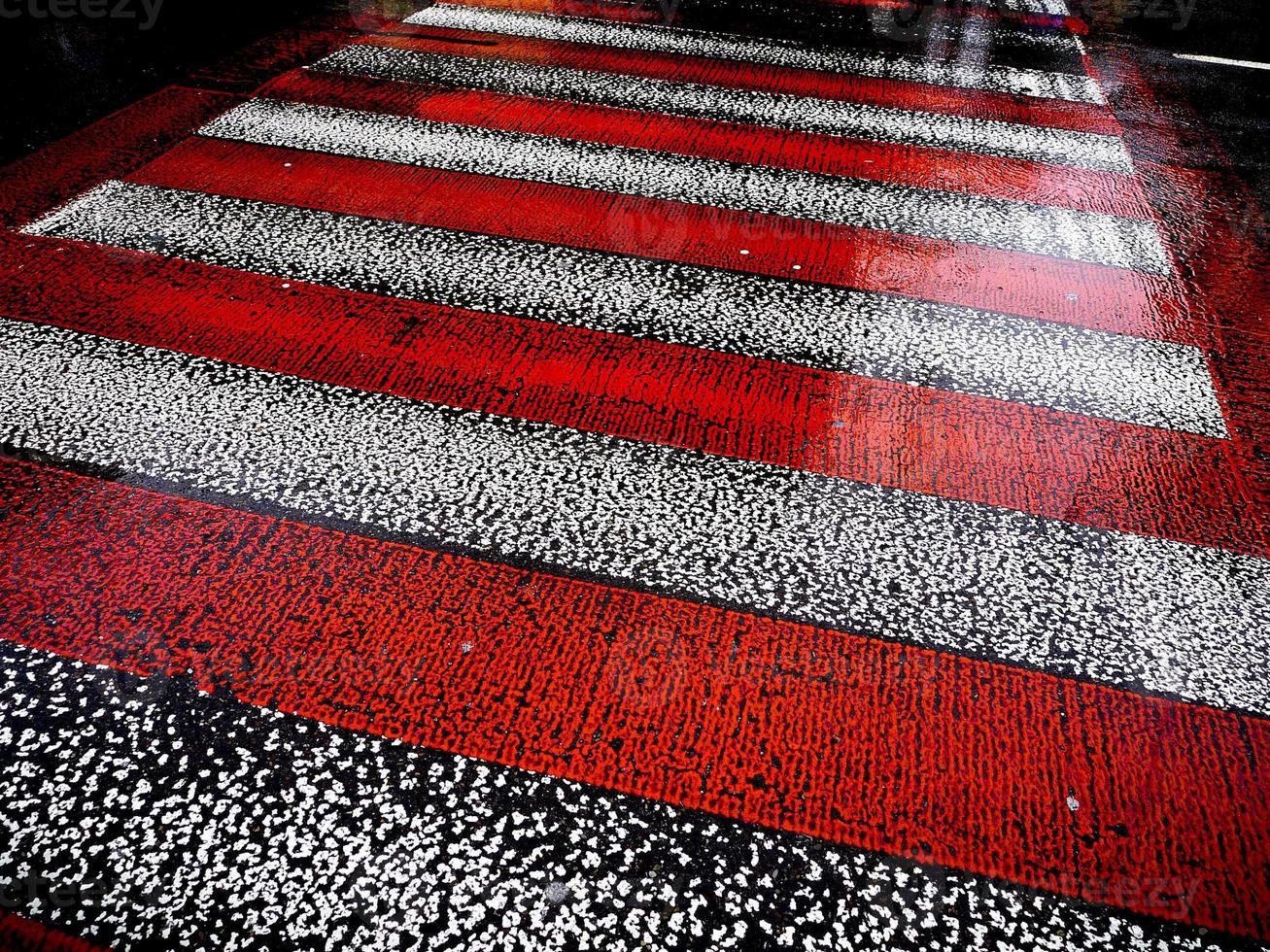 våt asfaltväg med röda och vita ränder för övergångsställe. foto