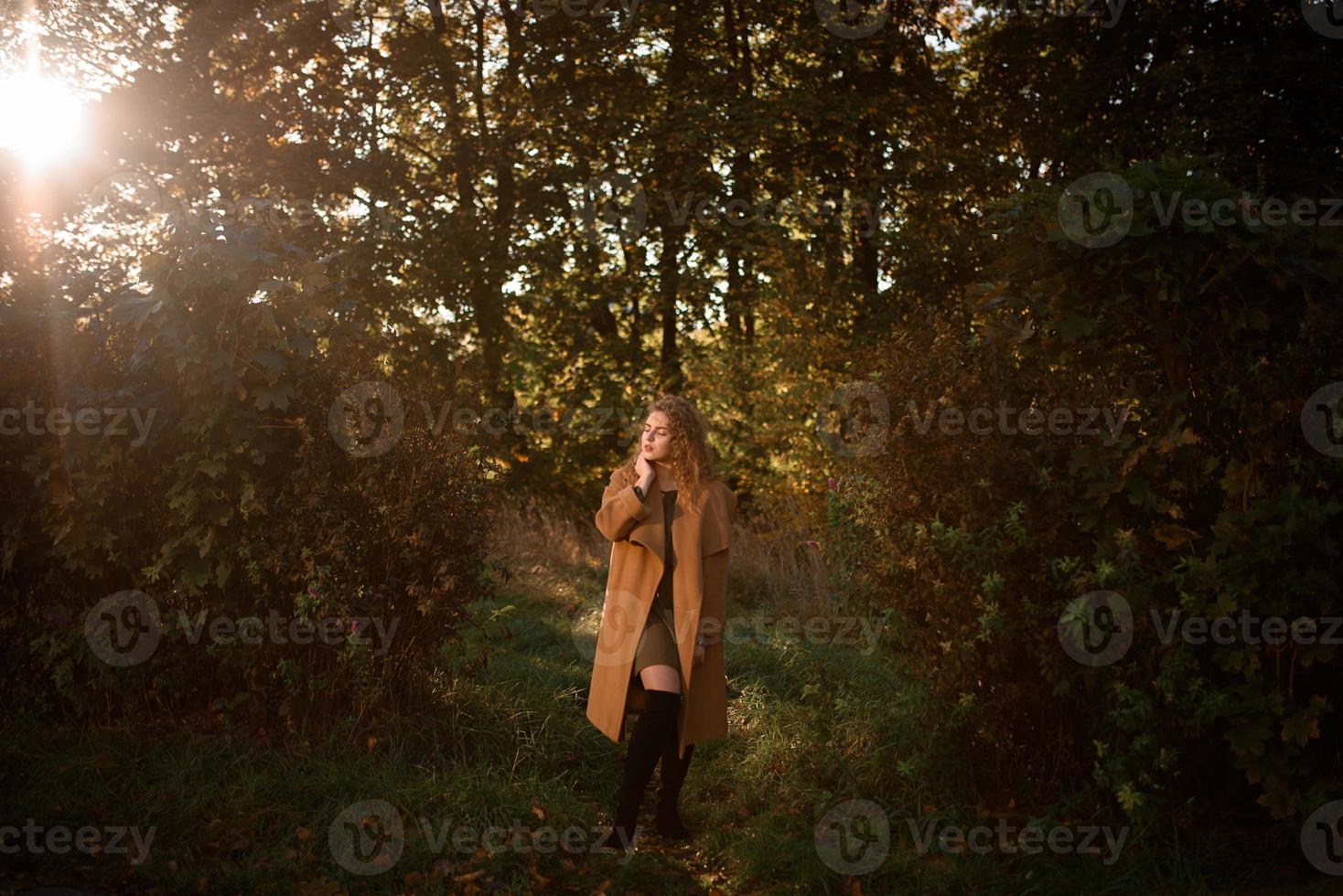 vacker elegant kvinna som står i en park på hösten foto