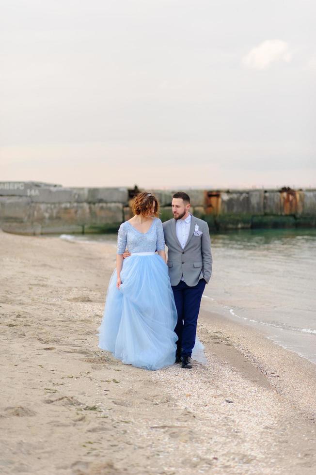 bröllop fotosession av ett par på stranden. blå bröllopsklänning på bruden. foto