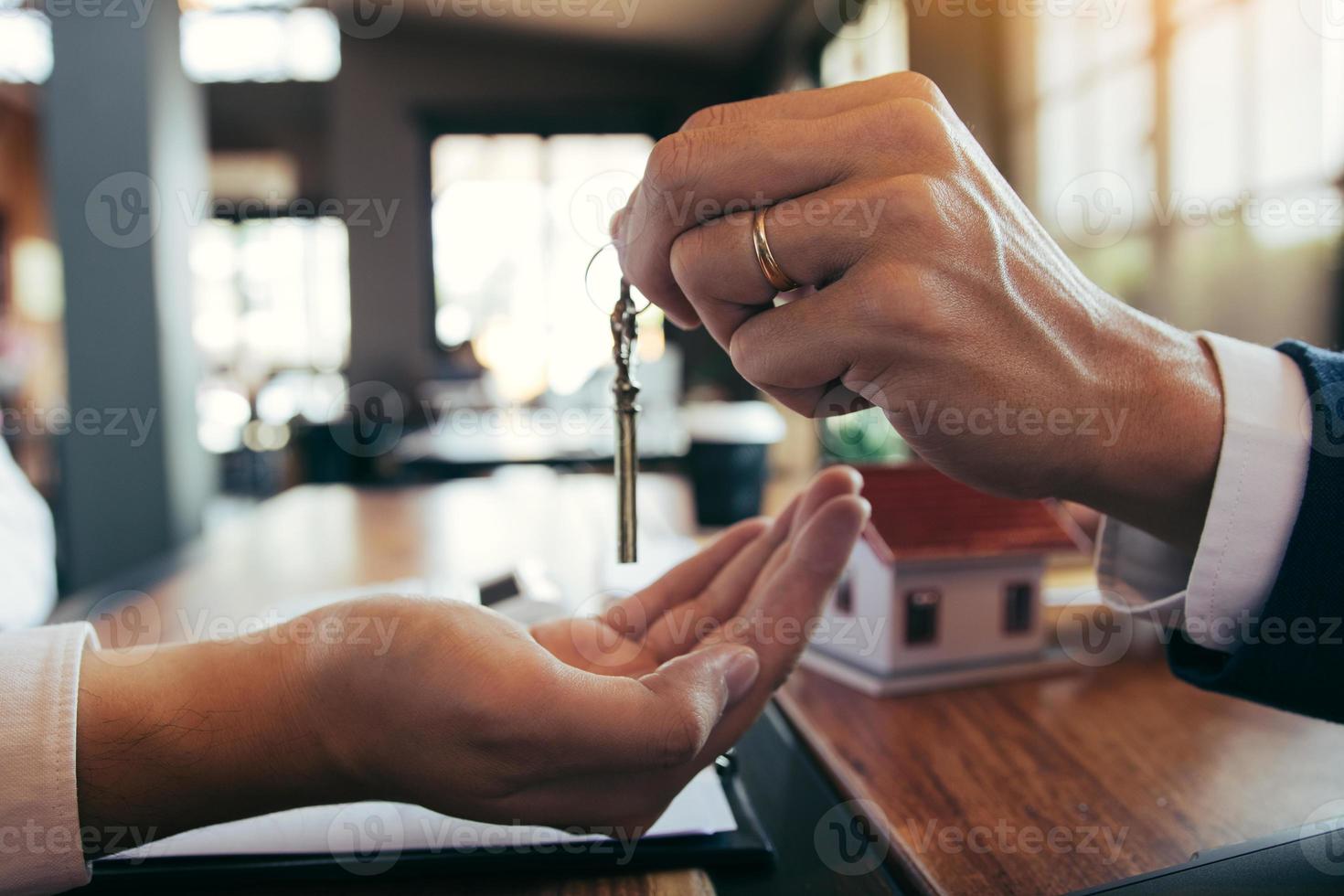 Närbild av husagenter delar ut nycklar till nya bostadsköpare. foto