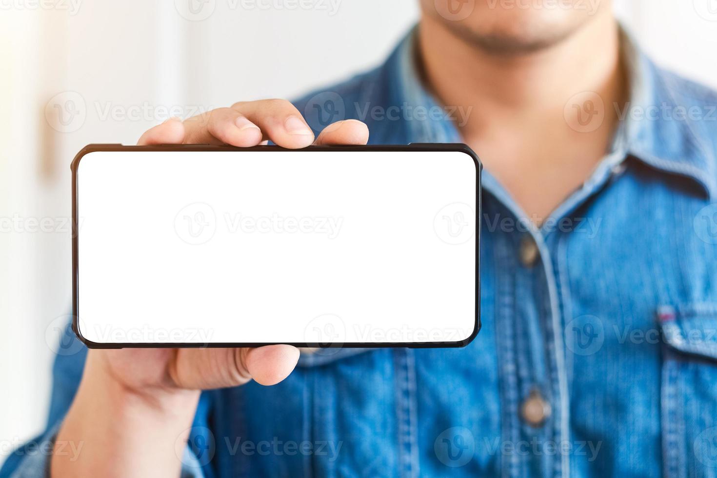 mockup kopia rymdtelefon, mannens hand som håller smartphone med tom vit kopia skärm för din reklam och meddelande eller information innehåll, mobil på skrivbordet på kaféet. foto