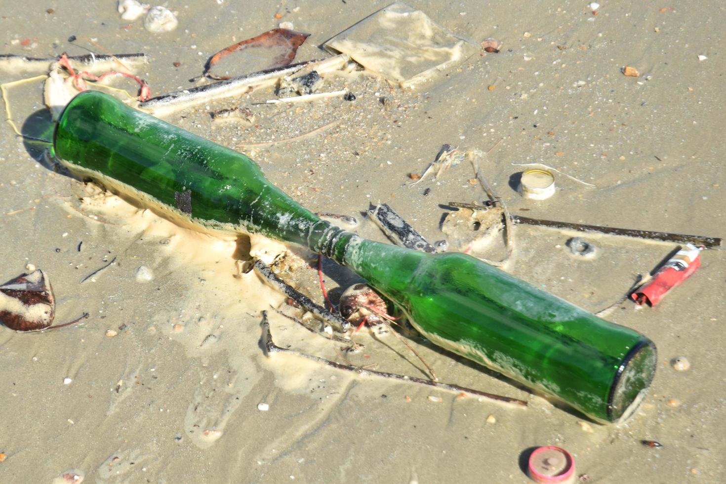 föroreningar och glasflaska på stranden från människor foto